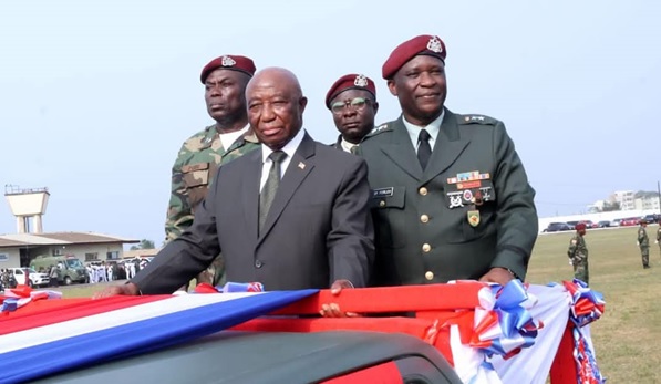 President Boakai and AFL Chief of Staff Kolleh and a group of men in military uniforms standing next to a car